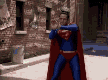 a man in a superman costume standing in front of a brick building
