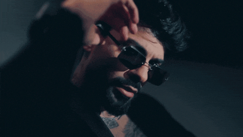 a man with a beard and sunglasses has a tattoo on his neck