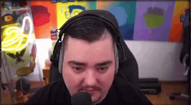 a man wearing headphones is talking into a microphone in front of a colorful wall .