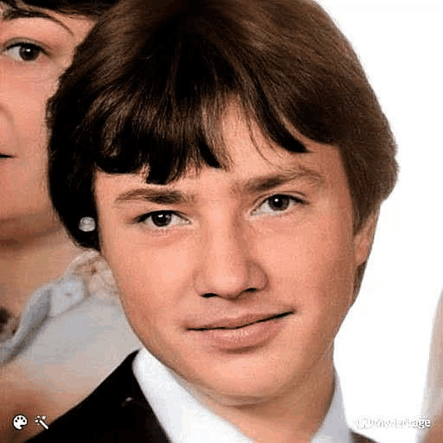 a close up of a young man 's face with a woman behind him .