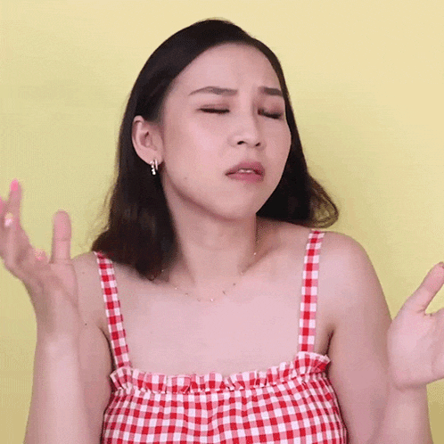 a woman in a red and white checkered tank top is making a face