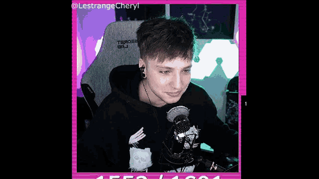 a man in a black hoodie is sitting in front of a microphone .