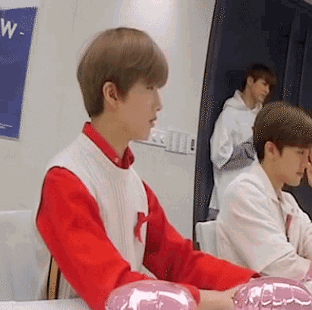 a man in a red and white sweater is sitting at a table holding a pink balloon .