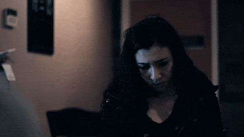 a woman in a dark room with a sign on the wall that says " no smoking "