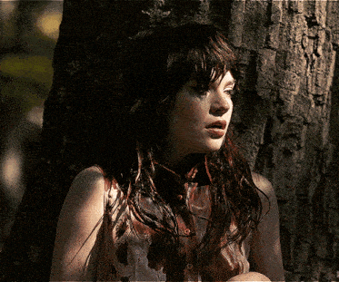 a woman leaning against a tree covering her face with her hand