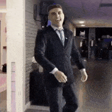 a man in a suit and tie is walking down a hallway and smiling .