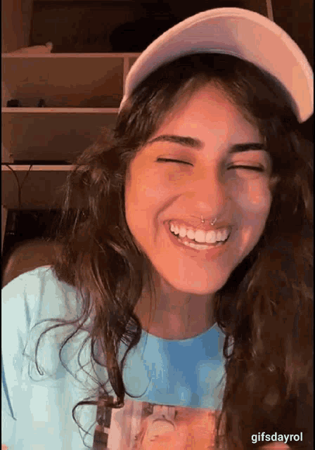 a woman wearing a white hat and a blue shirt is smiling with her eyes closed