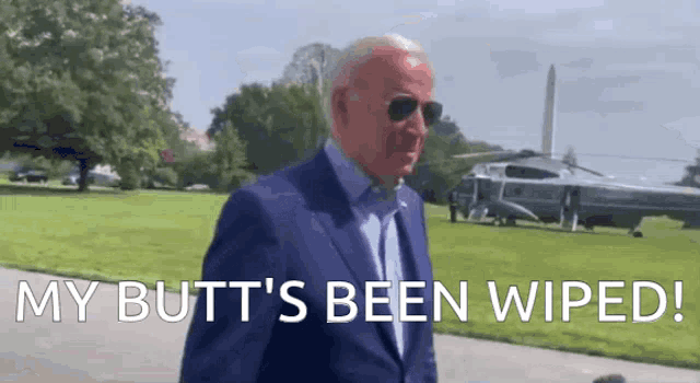 a man in a suit and sunglasses is walking in front of a helicopter and says `` my butt 's been wiped ''