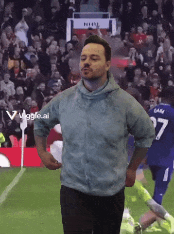 a man in a blue shirt is running on a soccer field with the number 27 behind him