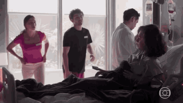 a group of people are standing around a woman in a hospital bed with an iv in her arm