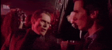 two men in suits and ties are talking to each other in a dark room .