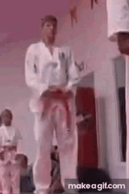 a man in a white karate uniform is standing on a stage .