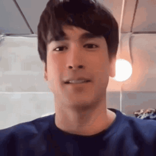 a close up of a man 's face wearing a blue shirt and smiling .