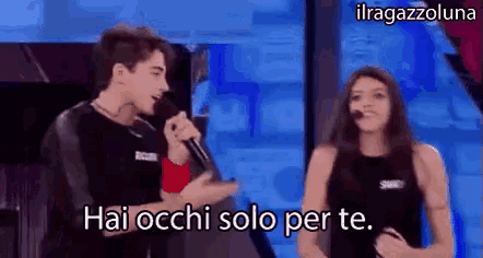 a man is singing into a microphone while a woman looks on and says hai occhi solo per te