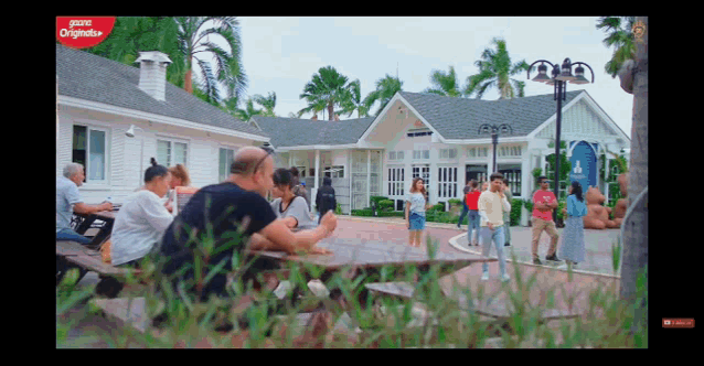 a group of people are sitting at a picnic table in front of a building that says ' prime originals ' on the bottom