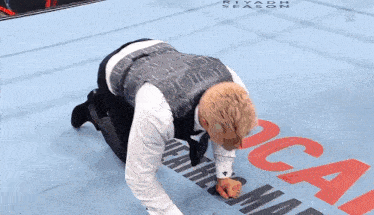 a man in a suit is kneeling down on a wrestling mat with the word riyadh season on it .
