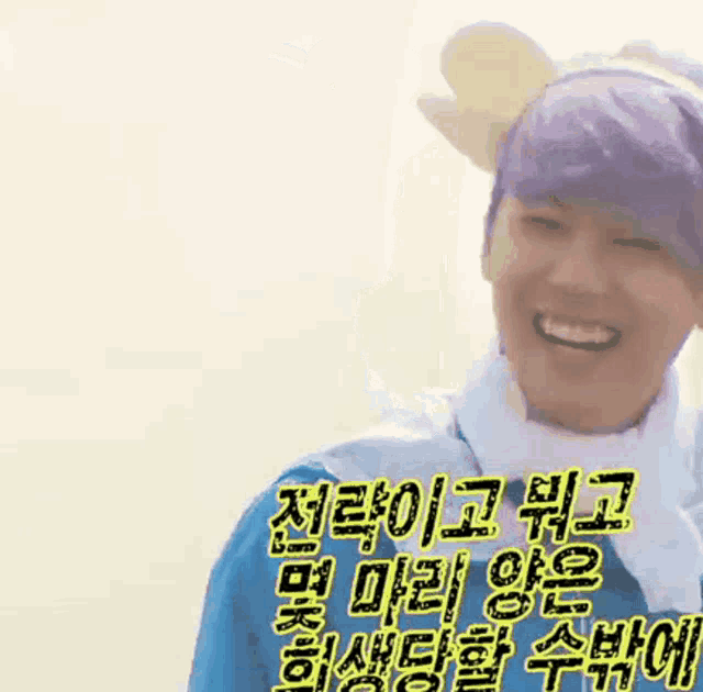 a man wearing a purple hat and a blue shirt is smiling in a korean language .