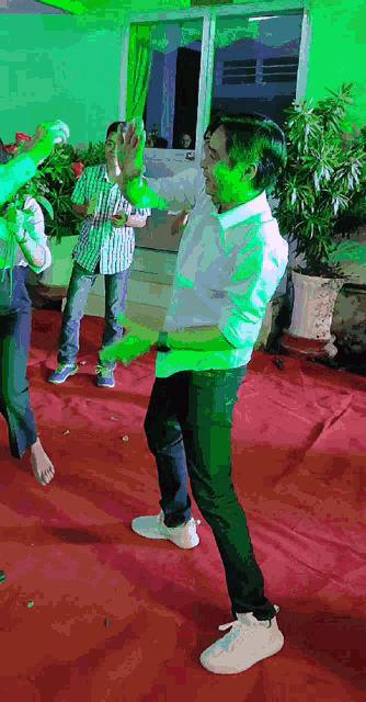 a man with green paint on his face is dancing in a room