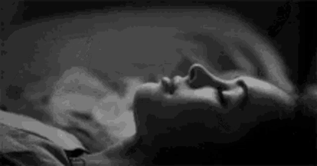 a woman is sleeping in a bed with her eyes closed and her mouth open .