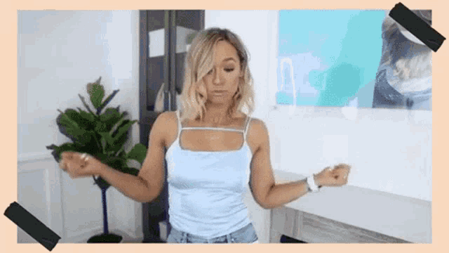 a woman in a blue tank top and denim shorts is dancing in a room .