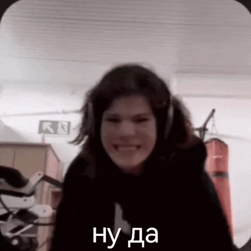 a woman wearing headphones is smiling and making a funny face in a dark room .