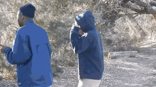 a man in a blue jacket stands next to another man in a blue jacket