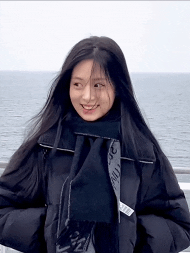 a woman wearing a black jacket and a black scarf with the word nyc on the front