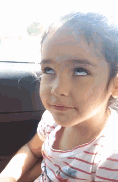 a little girl is sitting in the back seat of a car looking up