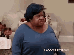 a woman is sitting in a living room wearing a blue shirt that says savonce on the bottom