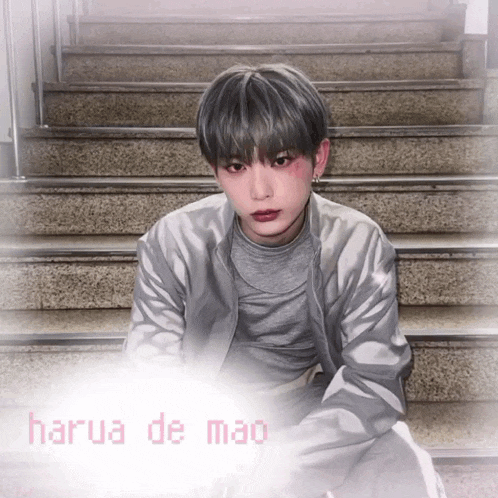 a man sitting on a set of stairs with harua de mao written in pink