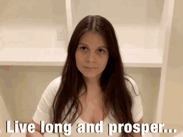 a woman says live long and prosper in front of a white shelf