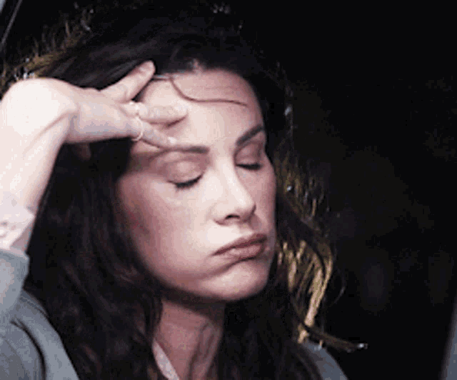 a woman with her hand on her forehead making a funny face