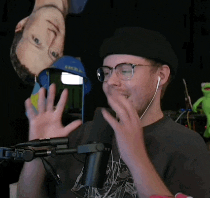 a man wearing glasses and a beret is sitting in front of a microphone .