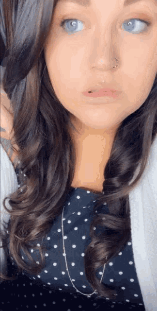 a woman with a nose ring is wearing a polka dot top