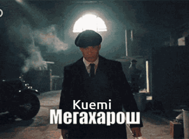 a man in a suit and tie is standing in a dark room with the name kuemi megaxapov on the bottom