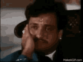 a man with a mustache is sitting in a chair with his hand to his face .