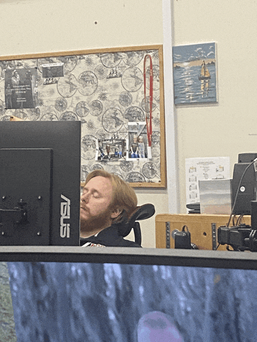a man sleeping in front of an asus computer