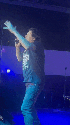 a man singing into a microphone while wearing a shirt that says ' i love you ' on it