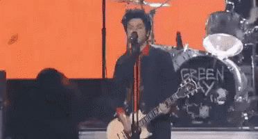 a man is playing a guitar and singing into a microphone while standing on a stage .