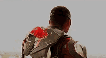 a man in a superhero costume with a red light coming out of his chest .