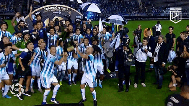 a group of soccer players are celebrating on a field with a trophy that says campeon 2019