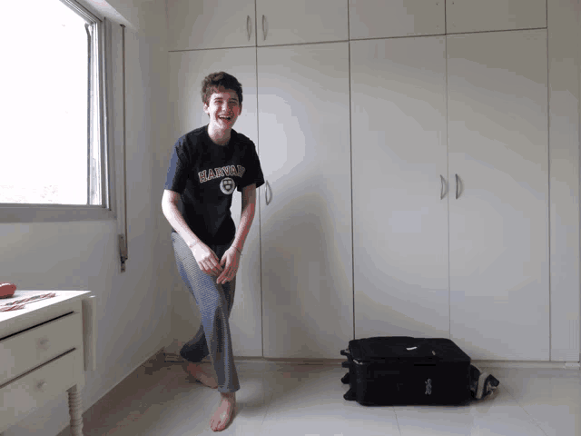 a boy wearing a shirt that says harvard is standing in a room