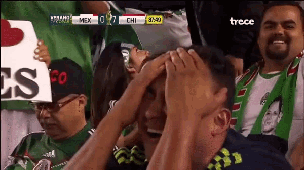 a man is covering his face while watching a soccer game between mexico and chi .