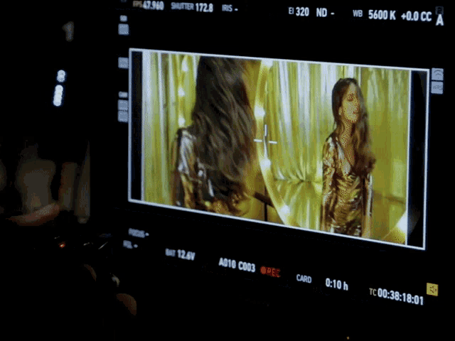 a screen shows a woman dancing in front of a yellow background