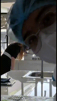 a woman in a surgical gown looks down at something in front of a sink that says rota on it