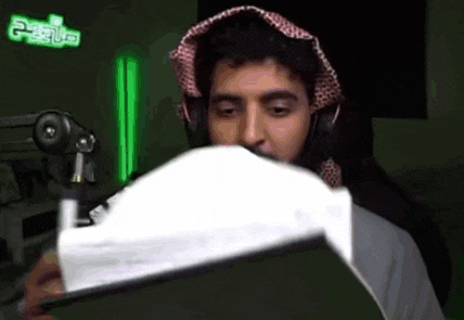 a man wearing headphones and a turban is holding a piece of paper in front of a microphone .