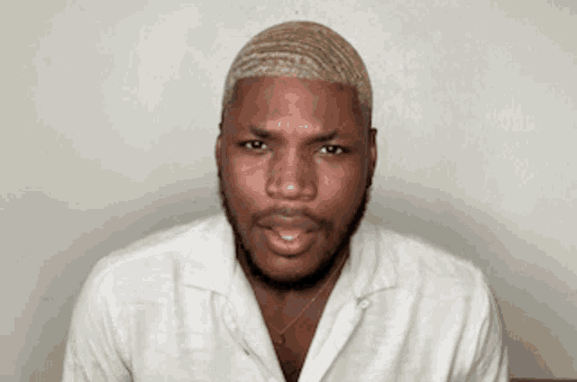 a man with a beard is wearing a white shirt and making a funny face