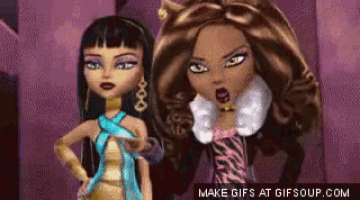 two monster high dolls are standing next to each other and looking at each other .