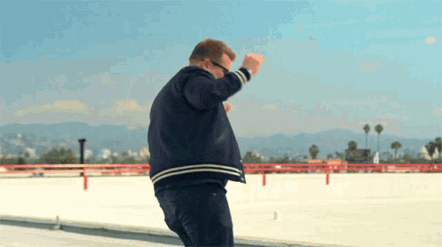 a man in a black jacket is dancing on a roof