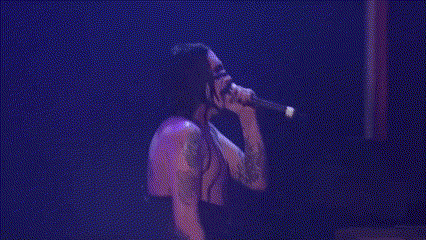 a shirtless man is singing into a microphone on a stage